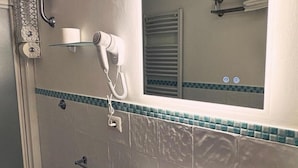 Casa de banho com secador de cabelo, toalheiro e espelho.
