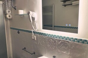 Ein Badezimmer mit Föhn, Handtuchhalter und Spiegel.