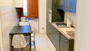 Uma cozinha compacta com mesa e cadeiras, fogão a gás e forno embutido.