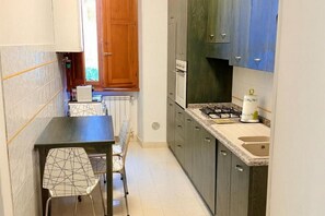 Eine kleine Küche mit Esstisch und Stühlen, einem Gasherd und einem eingebauten Backofen.