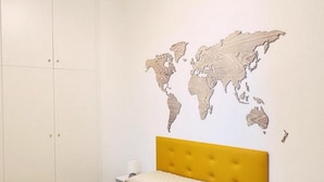 Um quarto com cama, mapa-múndi decorativo na parede e um guarda-roupa.