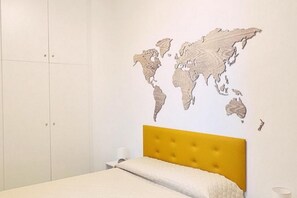 Ein Schlafzimmer mit einem Bett, einer Wanddekoration mit Weltkarte und einem Kleiderschrank.
