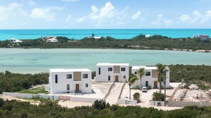A coastal property with three white buildings, a sandy beach, and a view of the ocean. - Spacious 4-bedroom house with Gorgeous Views from Every Room (Venetian Road)
