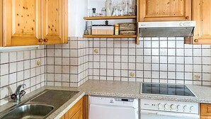 A kitchen with wooden cabinets, a stainless steel sink, a dishwasher, a stove, and a microwave.