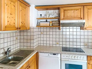 Una cocina con armarios de madera, un lavamanos de acero inoxidable, lavavajillas, estufa y microondas.