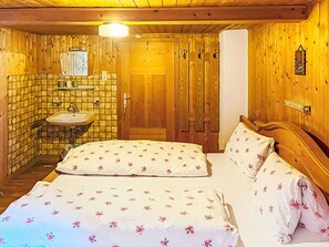A wooden room with a bed, a sink, and a door.