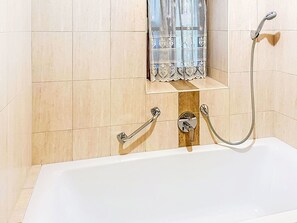 A bathroom with a bathtub, a shower, and a towel rack.