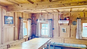 A wooden interior with a long table, benches, and curtains.