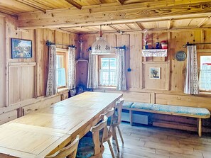 Un interior de madera con una mesa larga, bancos y cortinas.