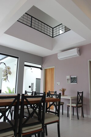 Un espace repas doté d’un haut plafond, d’un escalier et d’une vue sur la cuisine.