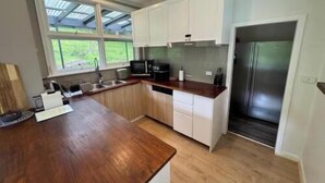 Cocina con encimeras de madera, refrigerador de acero inoxidable y ventana con vistas al verdor.
