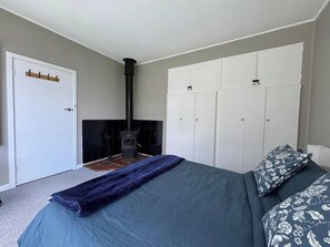 Ein Schlafzimmer mit Bett, Kleiderschrank, Kamin und einer Tür mit Kleiderhaken.