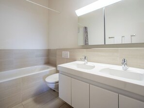 Une salle de bain moderne avec une baignoire, deux lavabos et des toilettes.