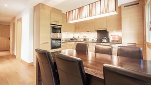 Une cuisine moderne avec un coin repas, comprenant une grande table en bois et des chaises en cuir.