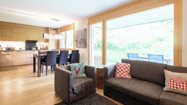 Un salon moderne comprenant un canapé, un fauteuil et un coin repas avec des chaises et une table.