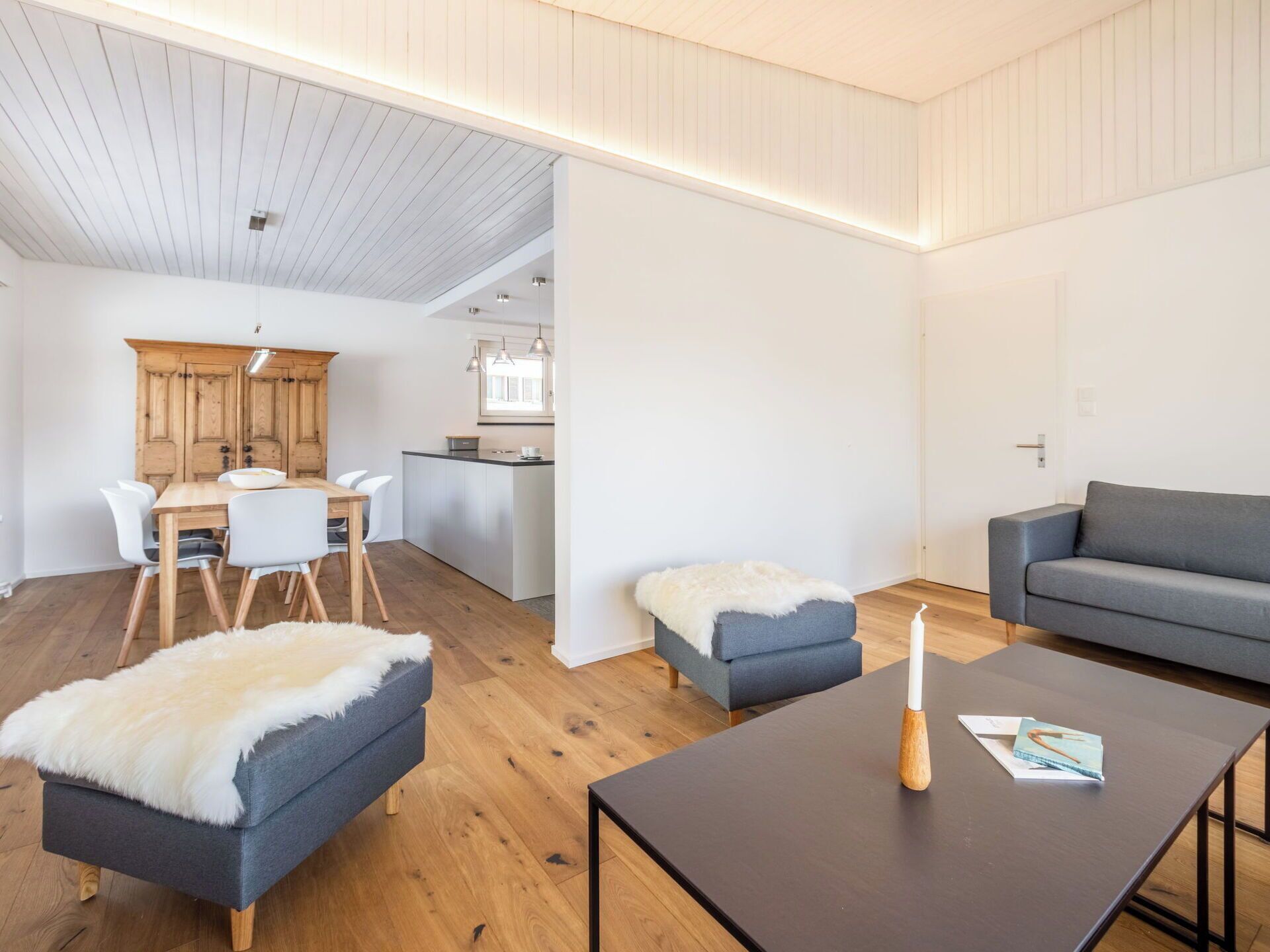 Un salon moderne avec un canapé, un pouf et une table basse.