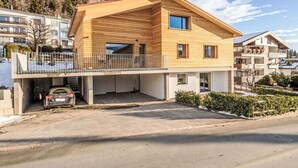 Una moderna casa a due piani con facciata in legno, un balcone e un garage.