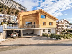 Ein modernes, zweistöckiges Haus mit Holzfassade, einem Balkon und einer Garage.