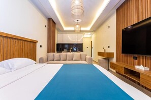 Ein modernes Hotelzimmer mit einem großen Bett, einem Fernseher, einer Küchenzeile und einer Wand mit Holzvertäfelung.