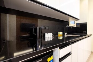 Eine moderne Küche mit schwarzem Arbeitsplatz, weißen Schränken, einer Kaffeemaschine und einem Spülbecken.