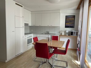 Una cucina moderna con pensili bianchi, un tavolo da pranzo in legno e sedie rosse.