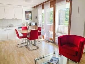 Una cuina moderna amb armaris blancs, una taula de dinar amb caires vermelles i una taula de cafè de vidre.