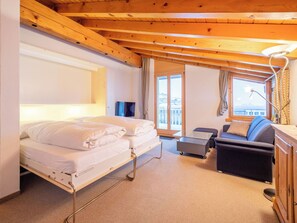 Habitación de hotel con cama, sofá, escritorio y vistas al exterior.