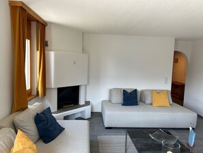 Ein modernes Wohnzimmer mit einer Couch, einem Fernseher und einem Kamin.
