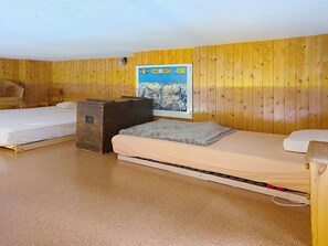 A room with two beds, wooden walls, a poster, and a suitcase. - Cosy apartment for 4 guests with WIFI, TV, terrace, pets allowed and panoramic view (Sagogn)