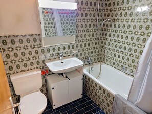 A bathroom with a toilet, sink, and bathtub, all with patterned tiles. - Cosy apartment for 4 guests with WIFI, TV, terrace, pets allowed and panoramic view (Sagogn)