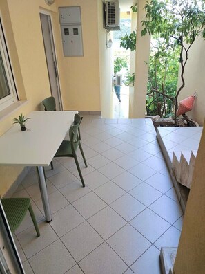 A small, tiled room with a table and chairs, a potted plant, and a view of greenery outside. - One bedroom apartment with terrace (Neum)