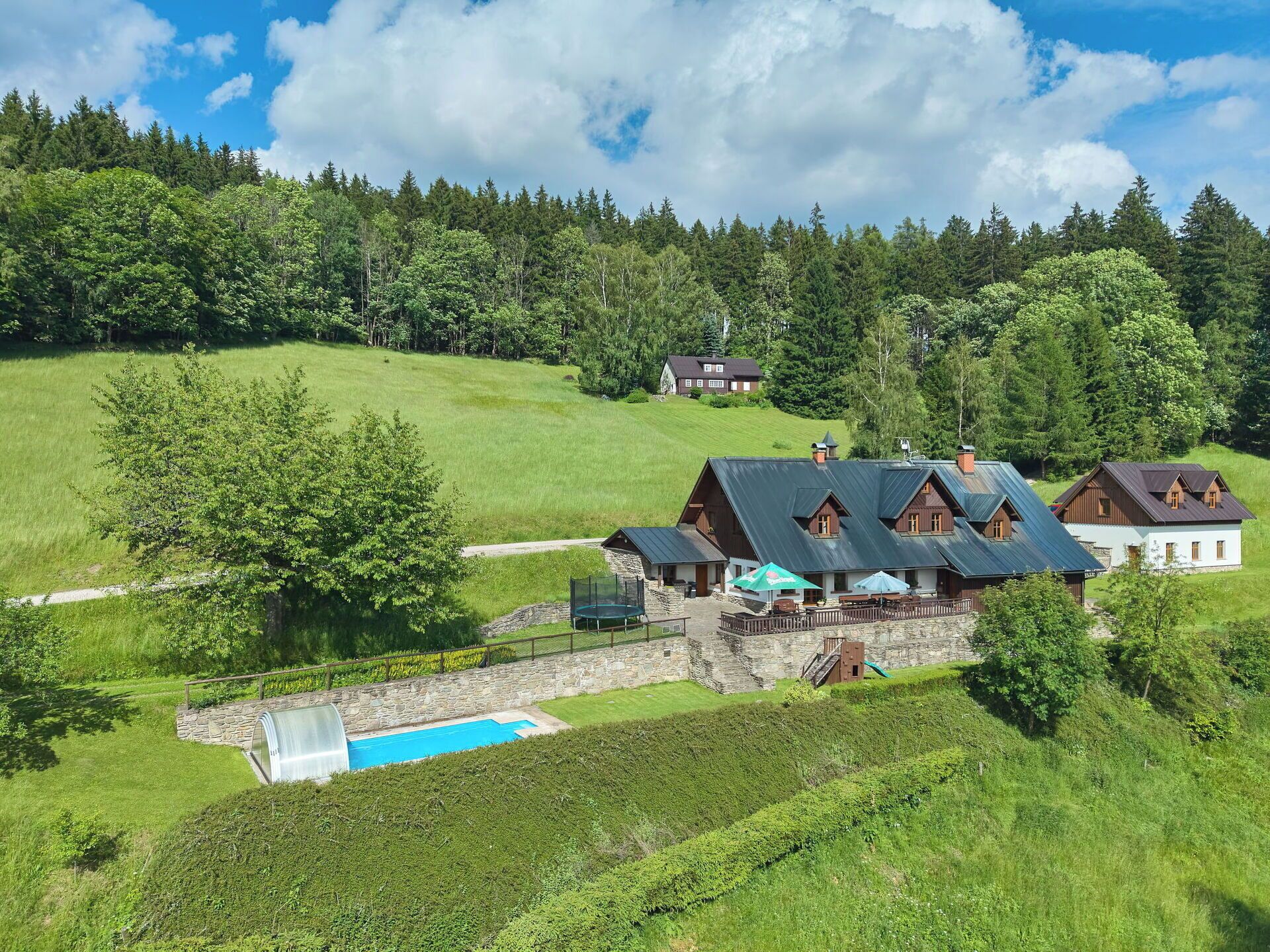Ein großes Haus mit mehreren Zimmern, einem Schwimmbad und einem umzäunten Spielbereich.