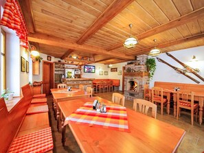 Interior em madeira com pé direito alto, lareira e vários espaços para sentar.