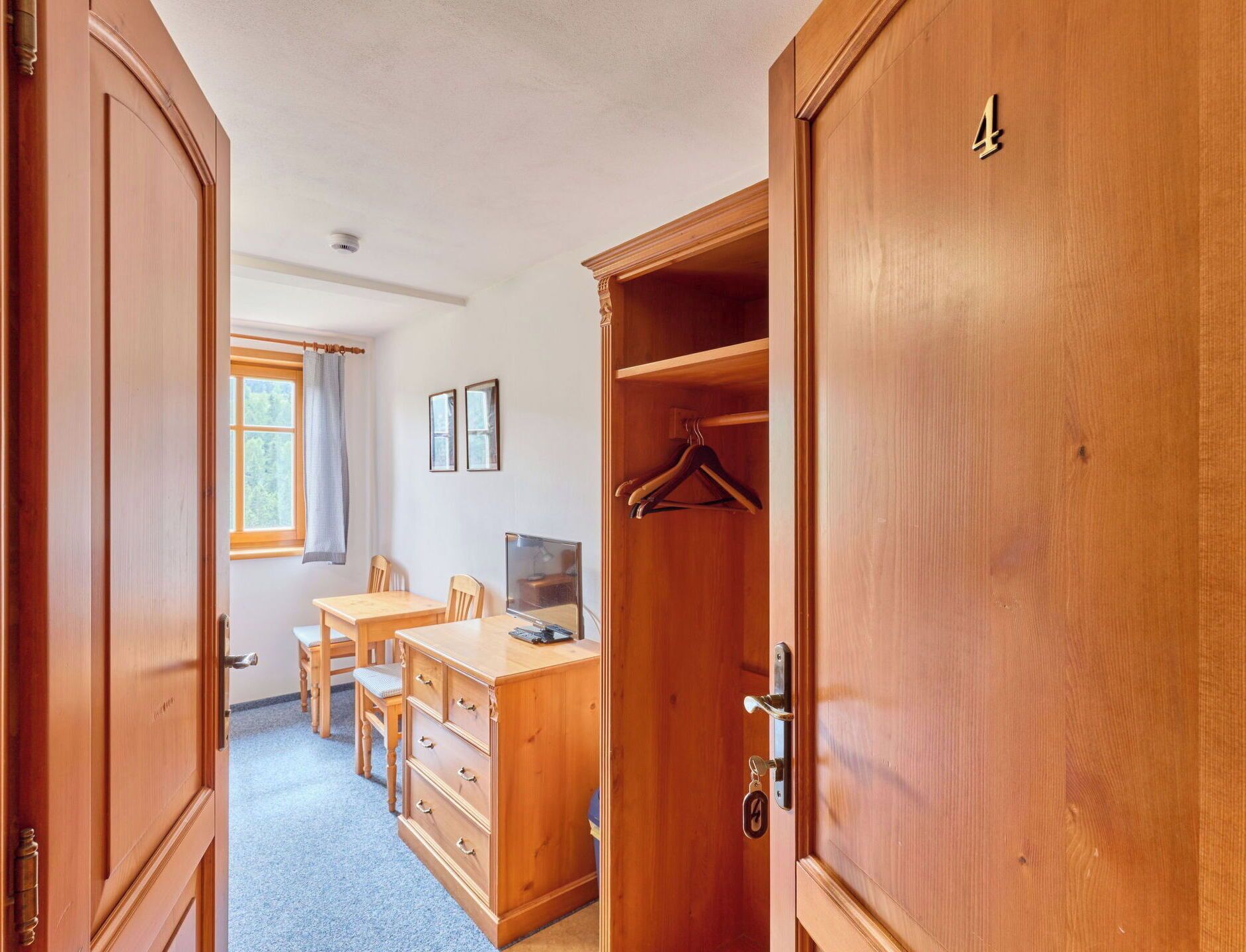 Une pièce comprenant un bureau, une chaise et une armoire avec une tringle pour suspendre les vêtements.