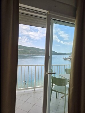 A balcony with a view of a lake, a boat, and distant hills. - One bedroom apartment (Neum)