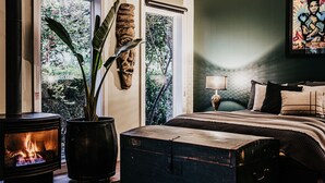 Ein gemütliches Schlafzimmer mit Bett, Nachttisch, Lampe, Kamin und Blick ins Grüne.