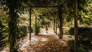 A brick pathway leading to a covered area with a statue, surrounded by greenery. - Istana Lodge - 5 Bed house on acreage with pool (Musk Vale)