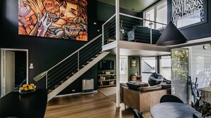 A multi-level living space with a staircase, a large mural, and a dining area. - Boatshed Villas by Istana - Yellow Door, villa near Lake Daylesford (Daylesford)