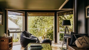 A room with large windows, a bean bag chair, a coffee table with books, and a lamp. - Boatshed Villas by Istana - Yellow Door, villa near Lake Daylesford (Daylesford)