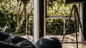 A room with a large window, a tripod, and a book on a cushion. - Boatshed Villas by Istana - Yellow Door, villa near Lake Daylesford (Daylesford)
