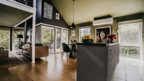A spacious living area with a high ceiling, a dining area, and a kitchen with a large island. - Boatshed Villas by Istana - Yellow Door, villa near Lake Daylesford (Daylesford)