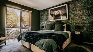 Un dormitorio con una cama grande, una ventana, un cuadro enmarcado y una radio.