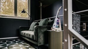 A modern living room with a sofa, a standing lamp, a guitar, and a radiator. - Boatshed Villas by Istana - Yellow Door, villa near Lake Daylesford (Daylesford)