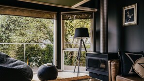 Ein modernes Wohnzimmer mit einem großen Fenster, einer schwarzen Stehlampe und einem Kamin.
