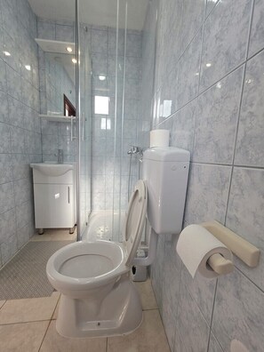 A modern bathroom with a toilet, bidet, and glass shower enclosure. - Apartment & Rooms Tempera / Apartment 1 (Neum)