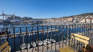 Ein Yachthafen mit vertäuten Booten, eine Brücke im Hintergrund und ein Hügel mit Gebäuden.