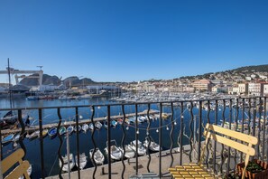 A marina with boats docked, a bridge in the background, and a hill with buildings. - The "Classé VIP", a balcony perched on the Old Port (La Ciotat)