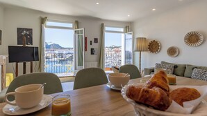 Ein Essbereich mit einem für das Frühstück gedeckten Tisch, einem Fernseher und Blick auf die Stadt.