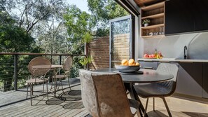 Un área de comedor al aire libre con una mesa, sillas y un cuenco de fruta.