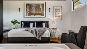 Un dormitorio moderno con una cama grande, mesitas de noche, una lámpara de pie y vistas por una ventana.